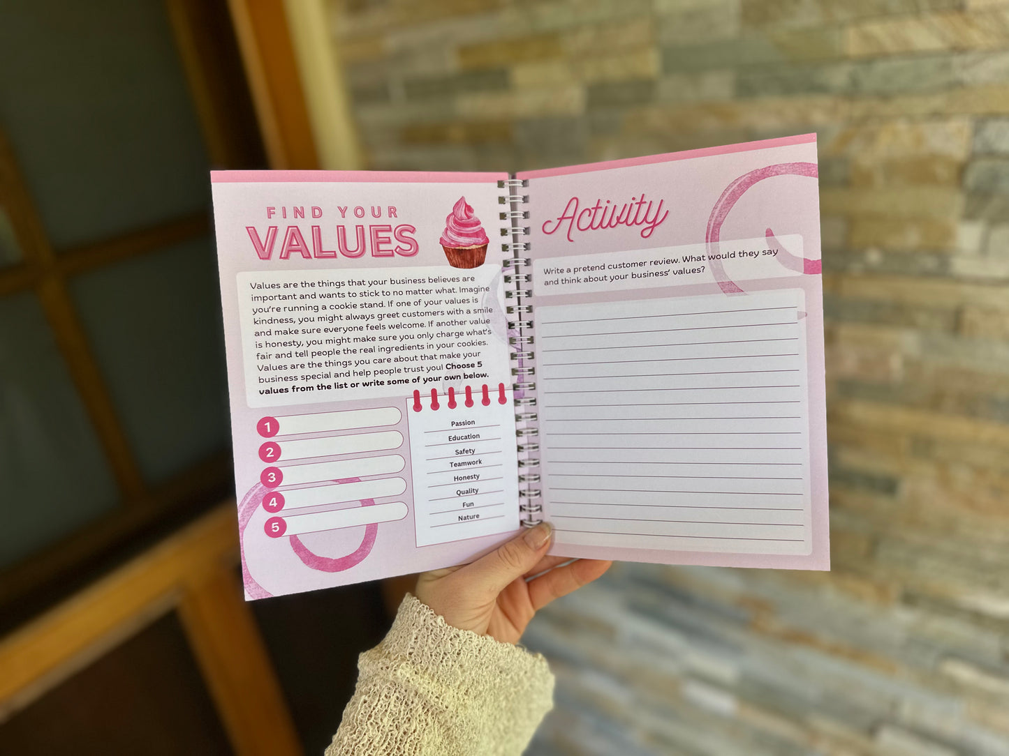 Branding section of the Via Pia Junior Business Guidebook, open to the values activity pages, held in hand.