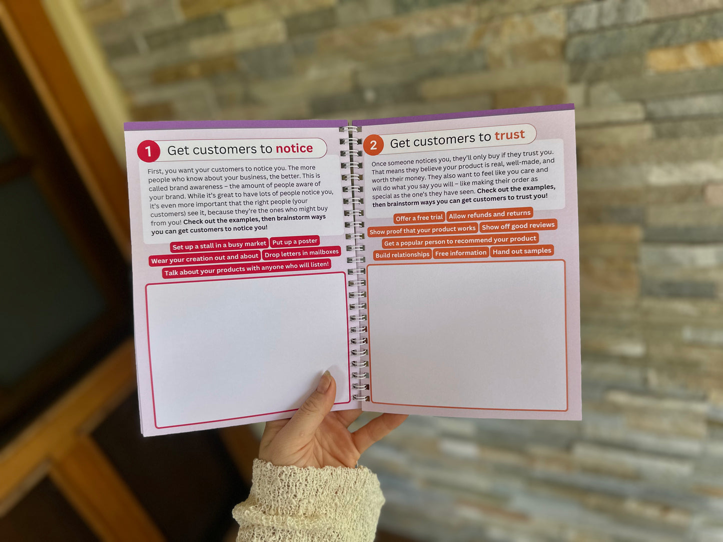 Marketing section of the Via Pia Junior Business Guidebook, open to the pages teaching how to get customers to notice and trust their mini business.