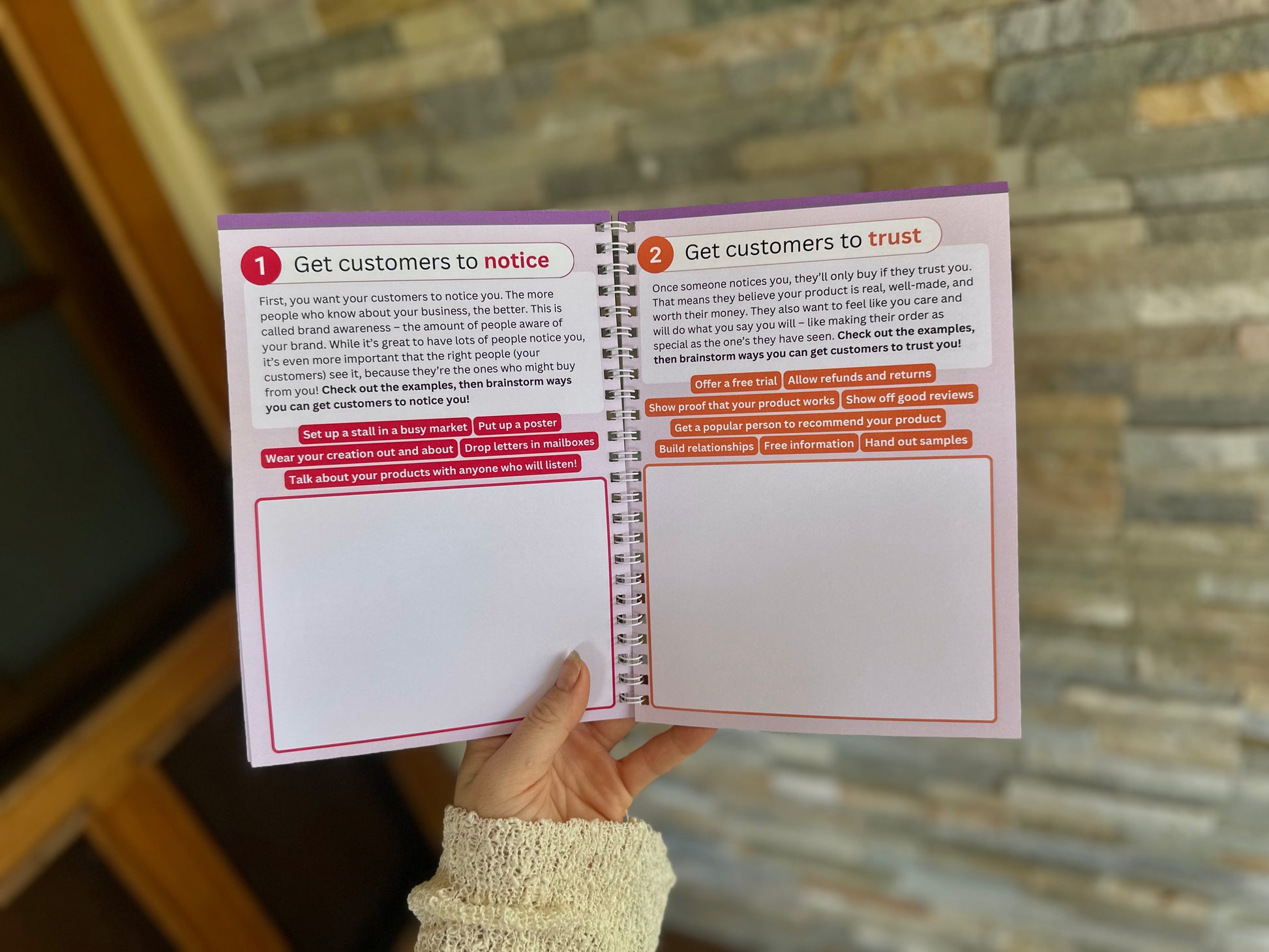 Marketing section of the Via Pia Junior Business Guidebook, open to the pages teaching how to get customers to notice and trust their mini business.